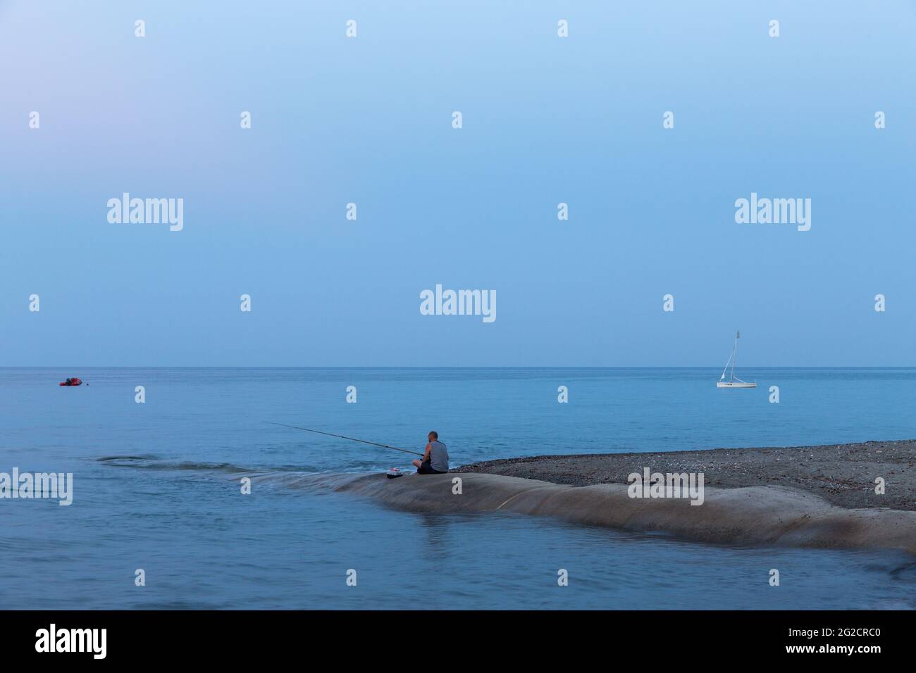 Pescatore seduto al mare alla notte. Moriani-Plage, Corsica. Francia Foto Stock