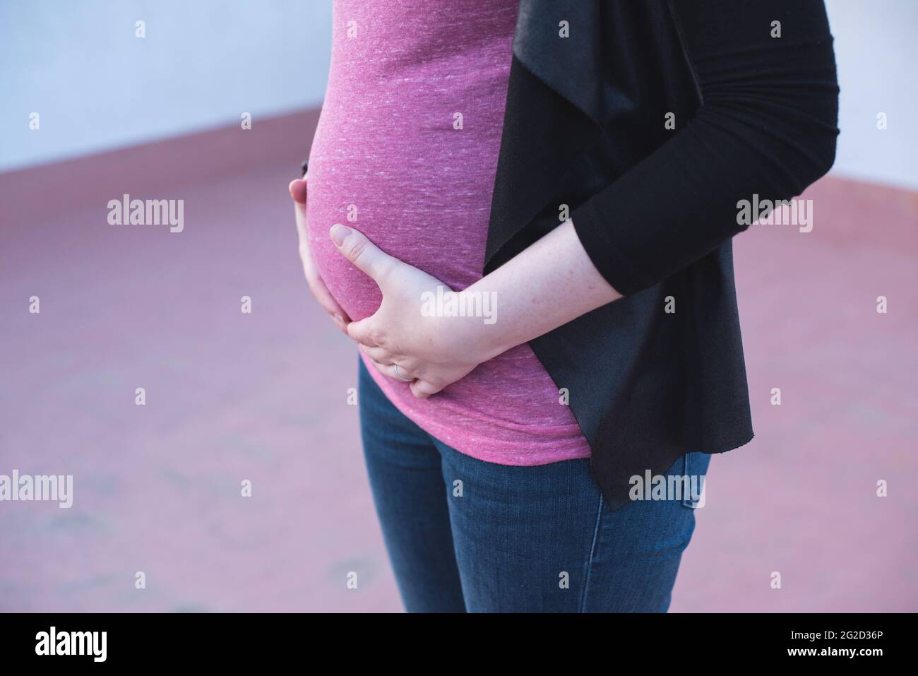 Primo piano di una donna che tocca il ventre incinta con le mani. Gravidanza Foto Stock