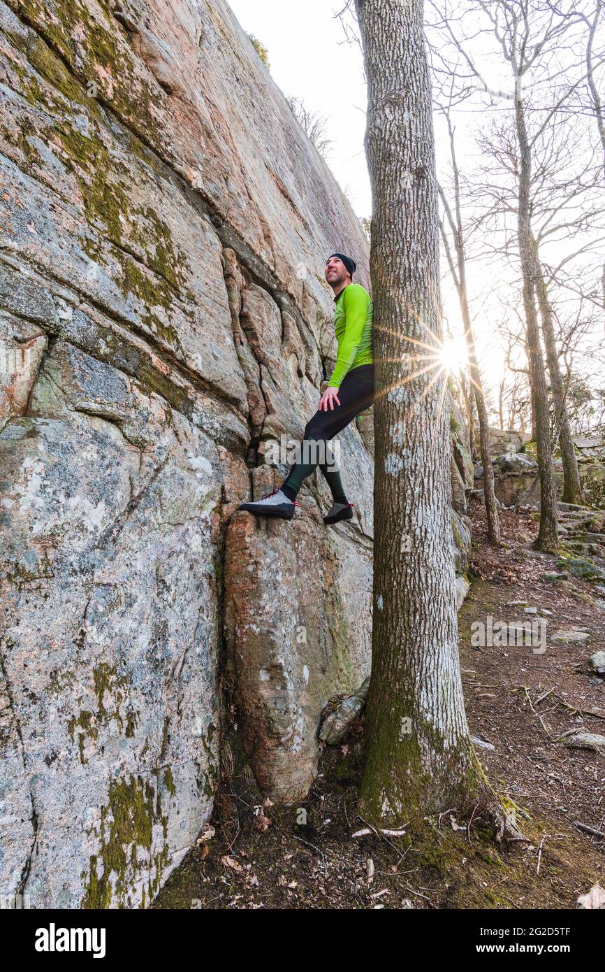 Uomo che arrampica su roccia in foresta Foto Stock