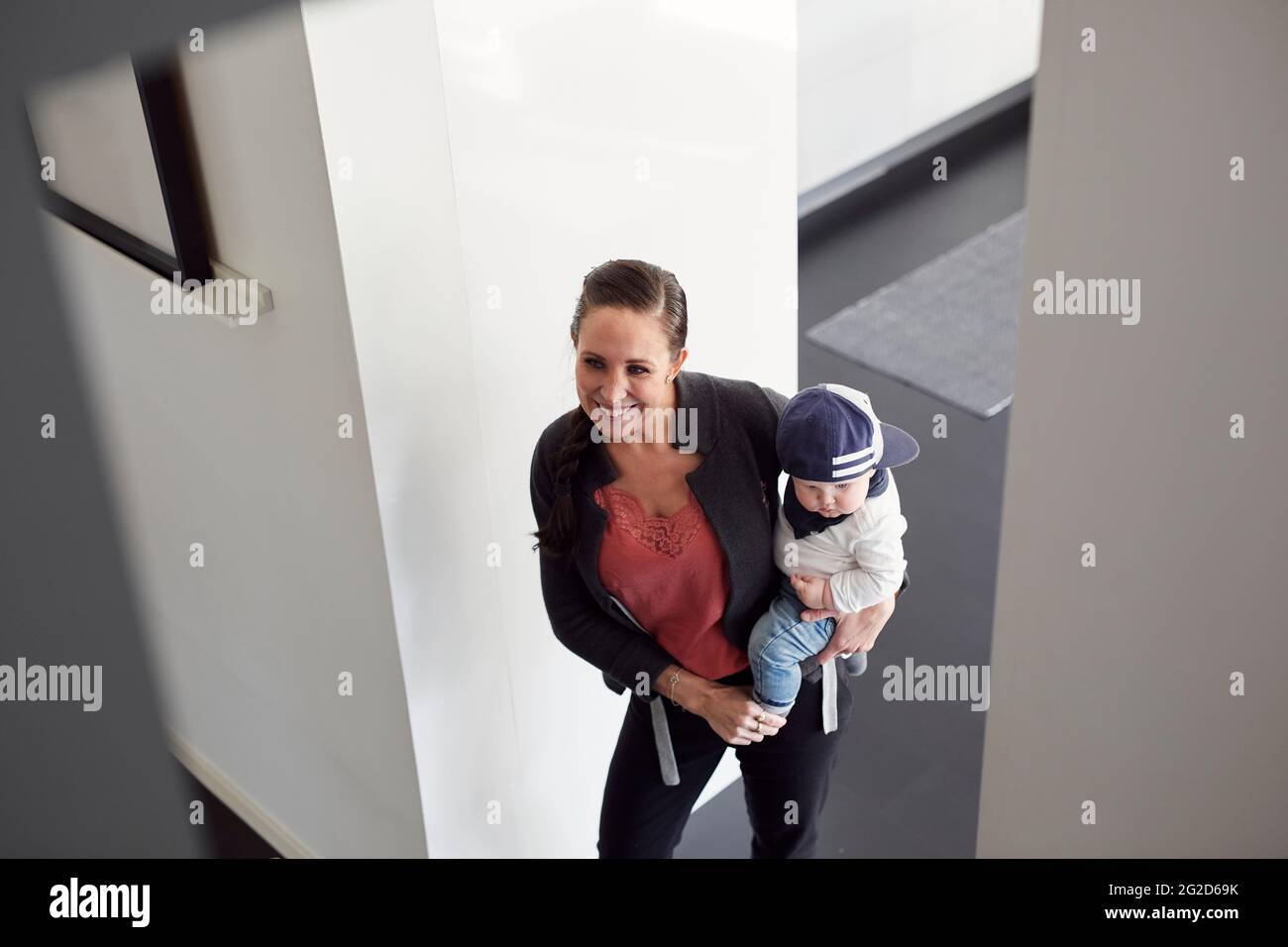 Donna sorridente che porta il figlio del bambino Foto Stock