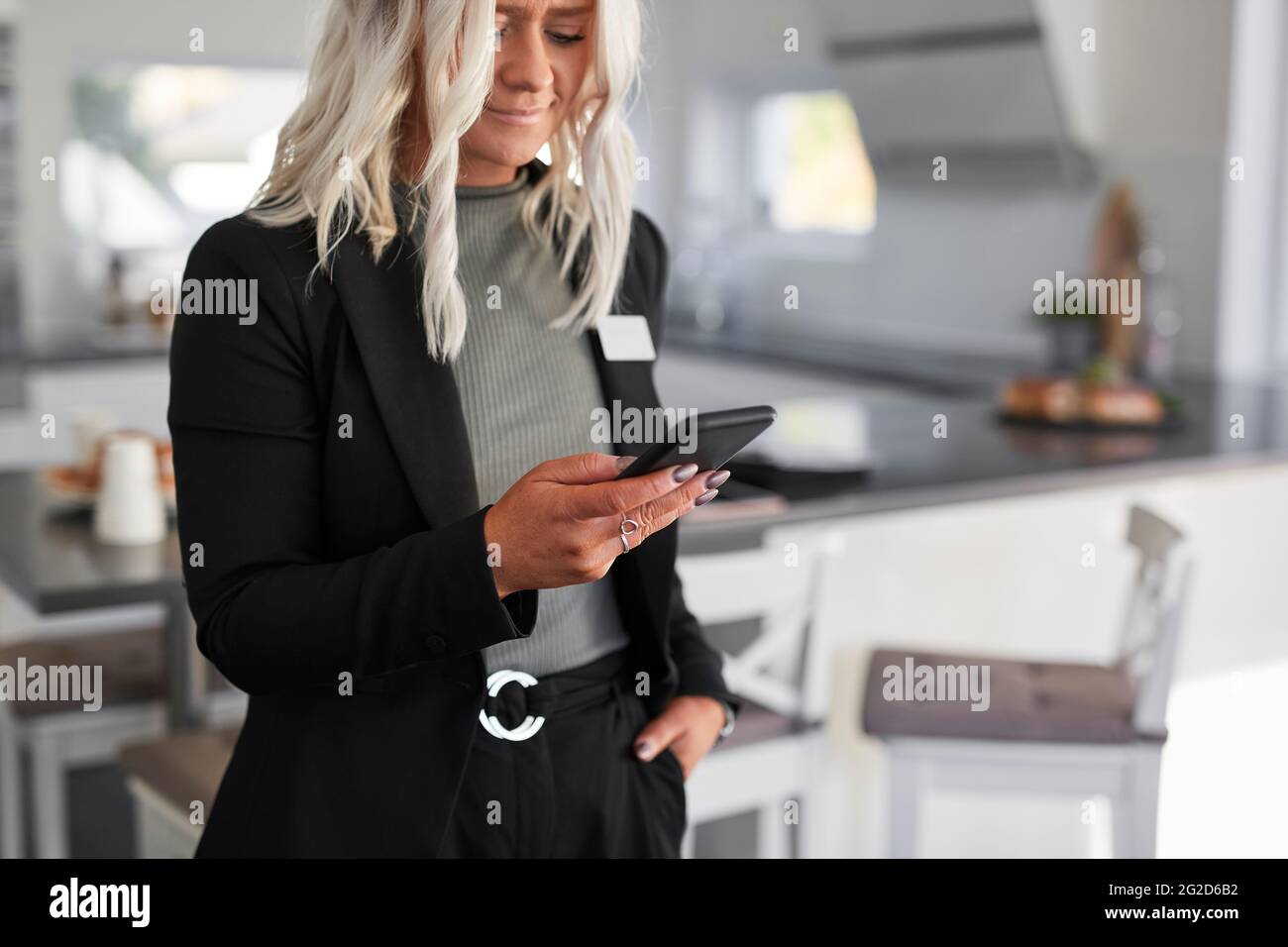 Agente immobiliare in casa moderna utilizzando il telefono cellulare Foto Stock