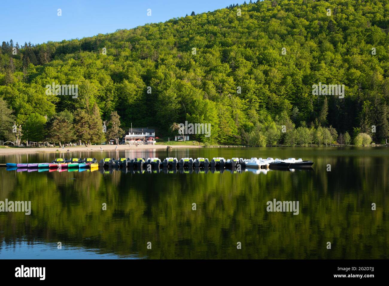 Lago di Chambon, Francia - 28 maggio 2021: Spiaggia del lago di Chambon con caffè e barche di svago in attesa di turisti. Parco Naturale Regionale dei Vulcani d'Alvernia. Foto Stock