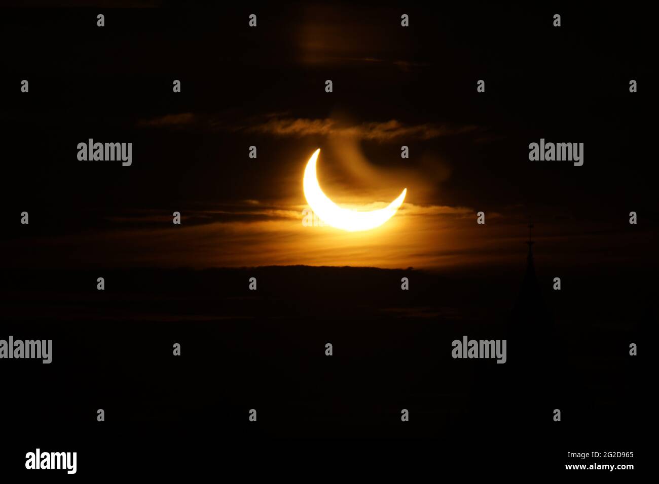 Ottawa, Canada. 10 giugno 2021: Un'eclissi solare parziale è vista sopra Parliament Hill a Ottawa, Canada - Giovedi, 10 giugno 2021. L'eclissi solare anulare o "anello di fuoco" è visibile solo ad alcune persone in Groenlandia, Russia settentrionale e Canada. Qui, il sole è visto al suo punto massimo di eclissi, a meno di 3 gradi sopra l'orizzonte a Ottawa. Credit: George Ross/Alamy Live News Foto Stock