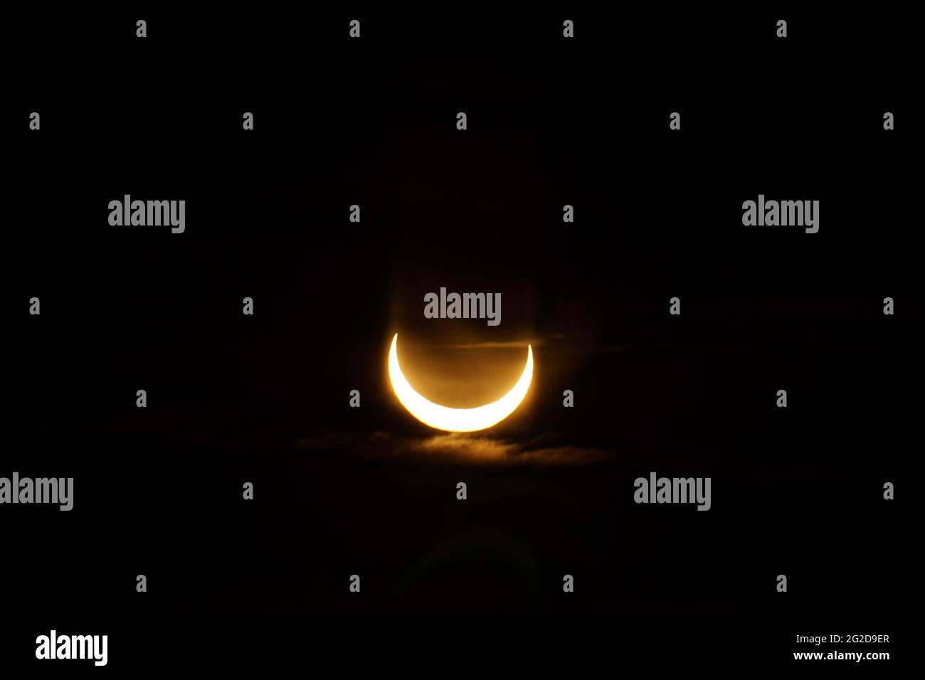 Ottawa, Canada. 10 giugno 2021: Un'eclissi solare parziale è vista sopra Parliament Hill a Ottawa, Canada - Giovedi, 10 giugno 2021. L'eclissi solare anulare o "anello di fuoco" è visibile solo ad alcune persone in Groenlandia, Russia settentrionale e Canada. Qui, il sole è visto al suo punto massimo di eclissi, a meno di 3 gradi sopra l'orizzonte a Ottawa. Credit: George Ross/Alamy Live News Foto Stock