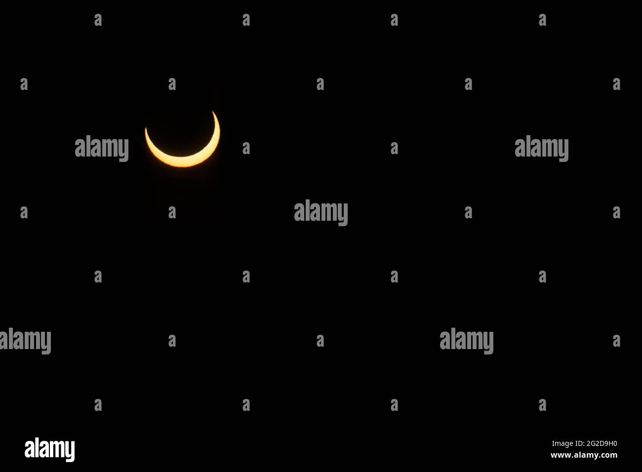 Ottawa, Canada. 10 giugno 2021: Un'eclissi solare parziale è vista sopra Parliament Hill a Ottawa, Canada - Giovedi, 10 giugno 2021. L'eclissi solare anulare o "anello di fuoco" è visibile solo ad alcune persone in Groenlandia, Russia settentrionale e Canada. Qui, il sole è visto al suo punto massimo di eclissi, a meno di 3 gradi sopra l'orizzonte a Ottawa. Credit: George Ross/Alamy Live News Foto Stock