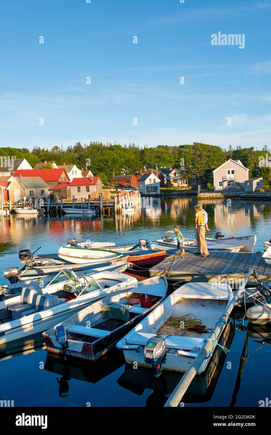 Bambini e uomo che guardano le barche ormeggiate a Carvers Harbour, Vinalhaven, Vinalhaven Island, Maine Foto Stock