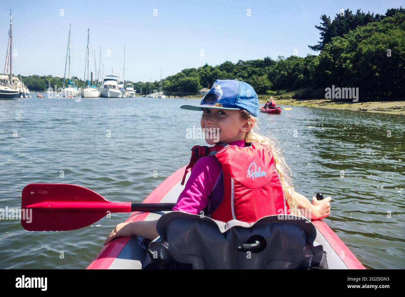 Una ragazza si siede di fronte a un kayak gonfiabile su un fiume nella New Forest. Foto Stock