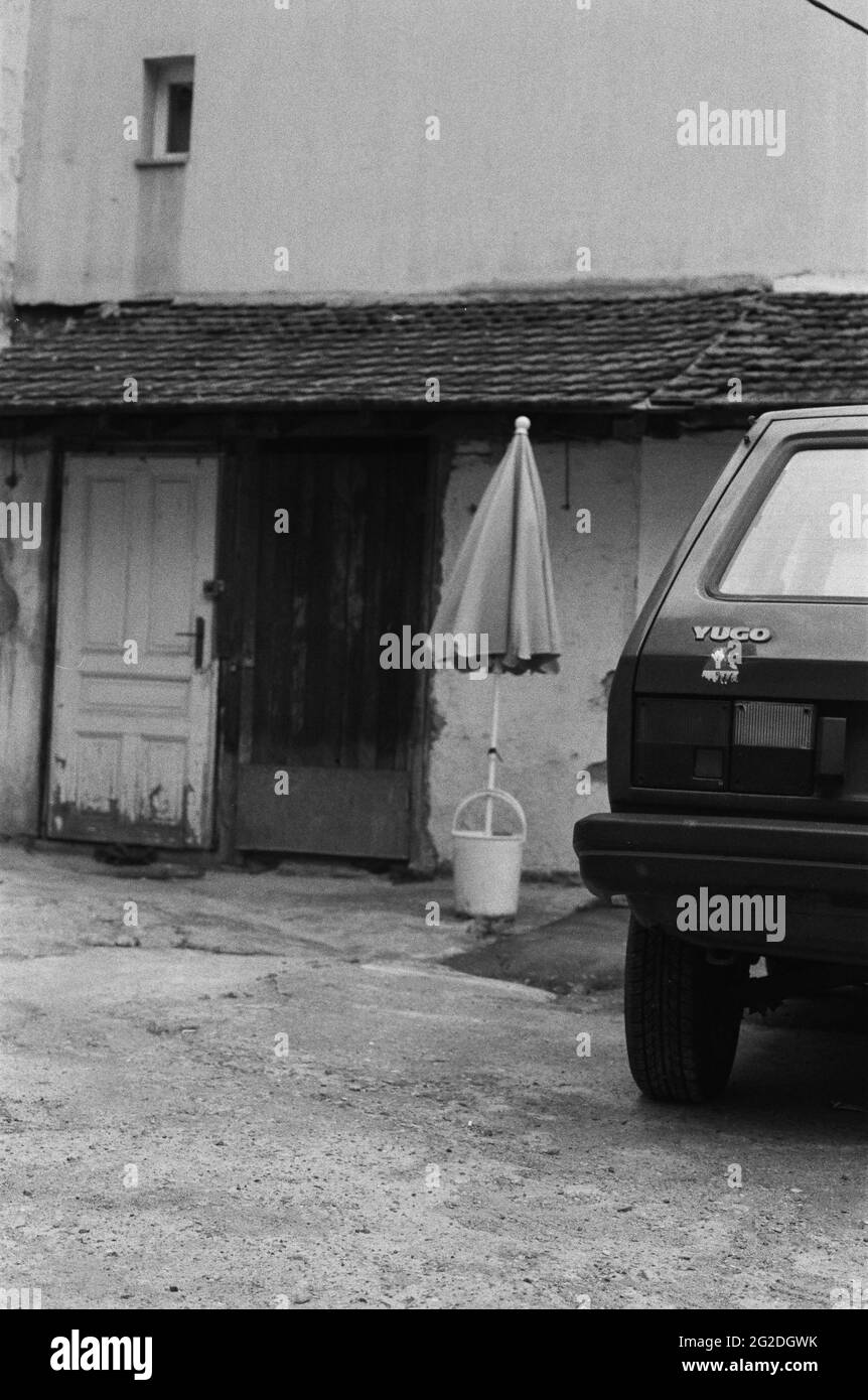 Auto Yugo davanti all'ombrellone in secchio di plastica di fronte al vecchio edificio Foto Stock