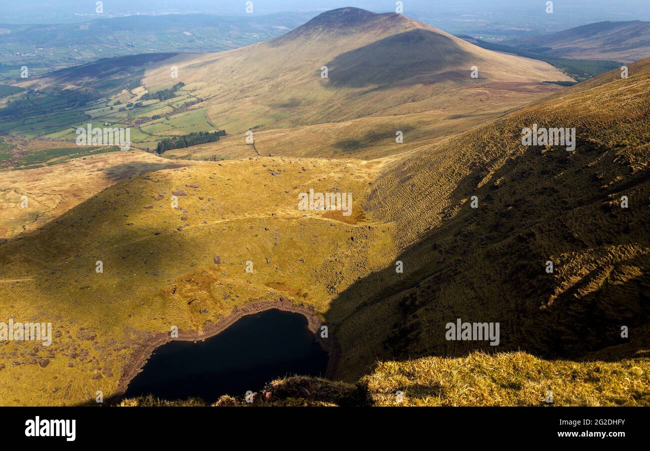 Tiny Lough Curra lago ai piedi del Galtymore Mountain Cliffs.Ireland. Foto Stock