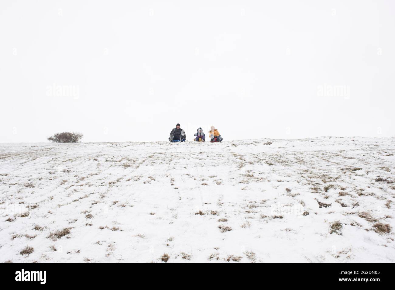 Una famiglia ha divertimento slitta su Mill Hill a Shoreham-by-Sea, West Sussex dopo una leggera copertura di neve a terra. Foto Stock