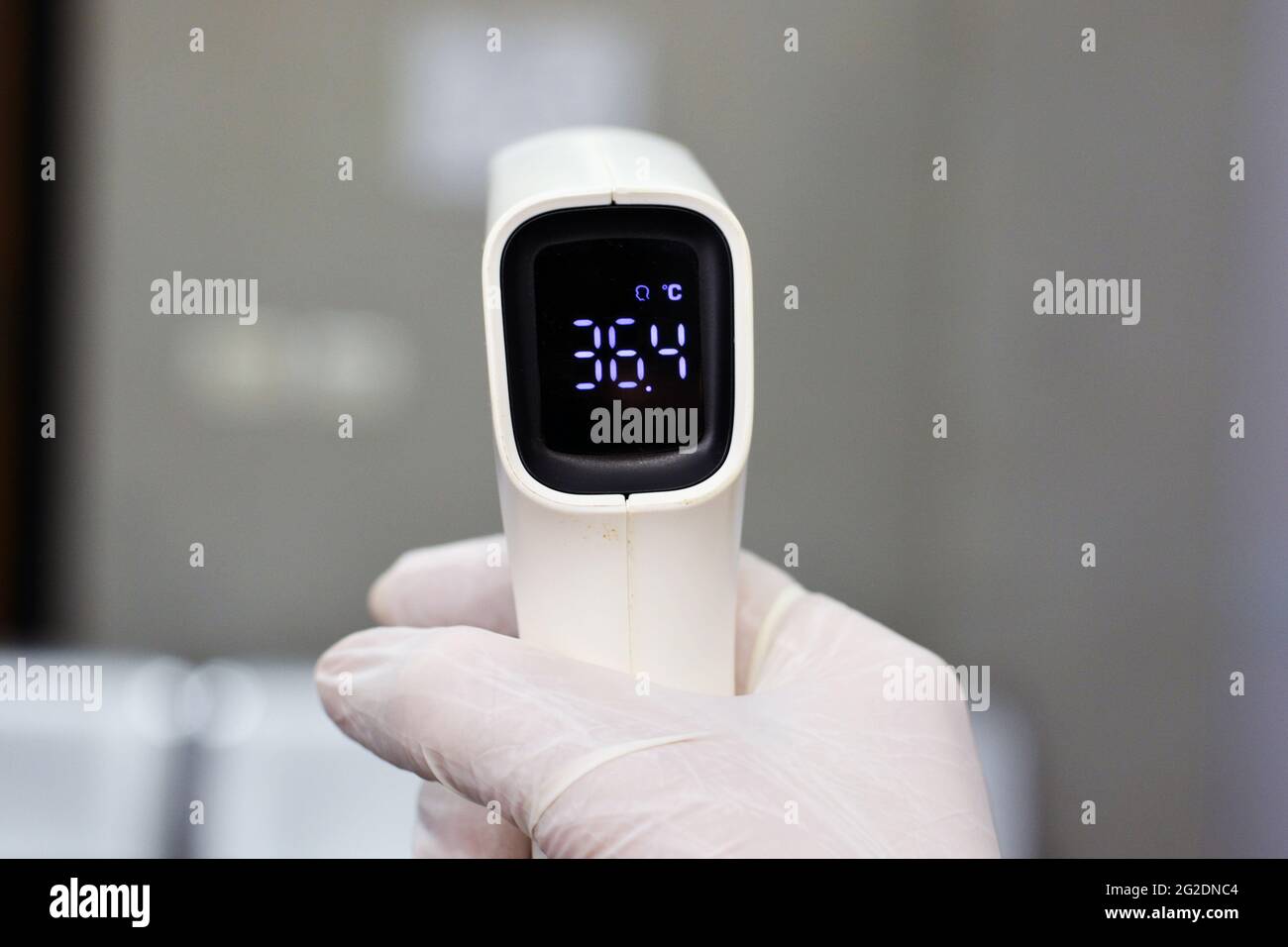 Termometro digitale per fronte a infrarossi senza contatto tenuto da un personale medico che controlla la temperatura corporea per i sintomi del virus Foto Stock