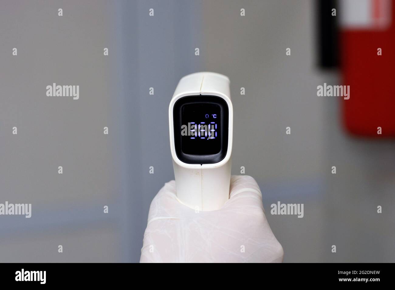 Termometro digitale per fronte a infrarossi senza contatto tenuto da un personale medico che controlla la temperatura corporea per i sintomi del virus Foto Stock