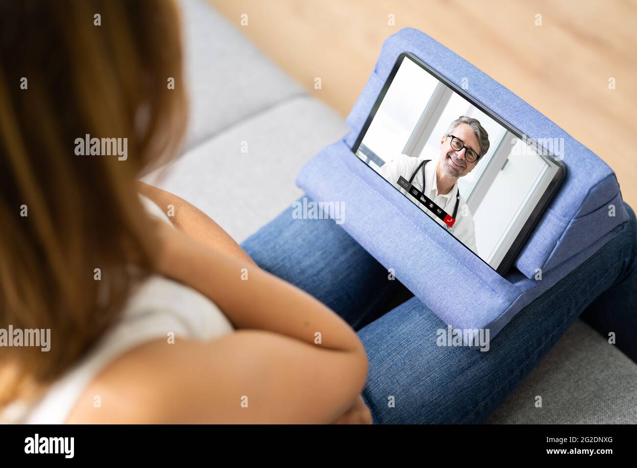 Donna che ha una chat video con Dottore Femminile su un tablet digitale a casa Foto Stock