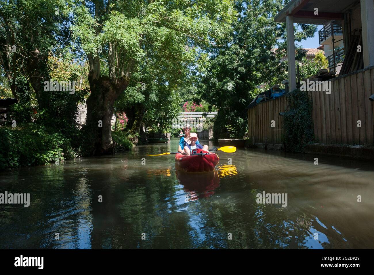 Una famiglia kayak nel Parco Naturale Regionale del Marais Poitevin su kayak gonfiabili in una vacanza estiva in Francia Foto Stock