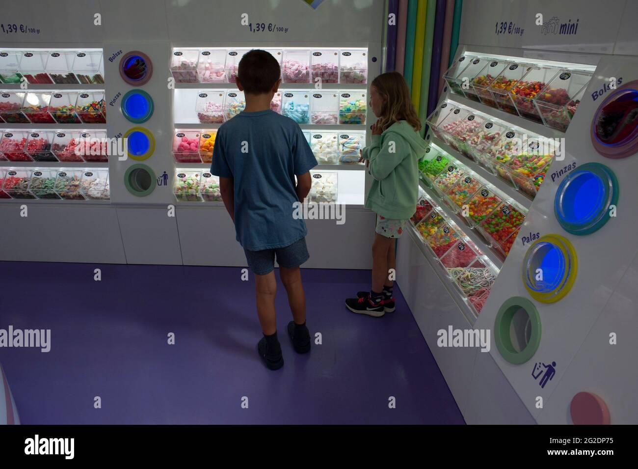 I bambini in un negozio di dolci che guarda la colorata esposizione di delizie Foto Stock