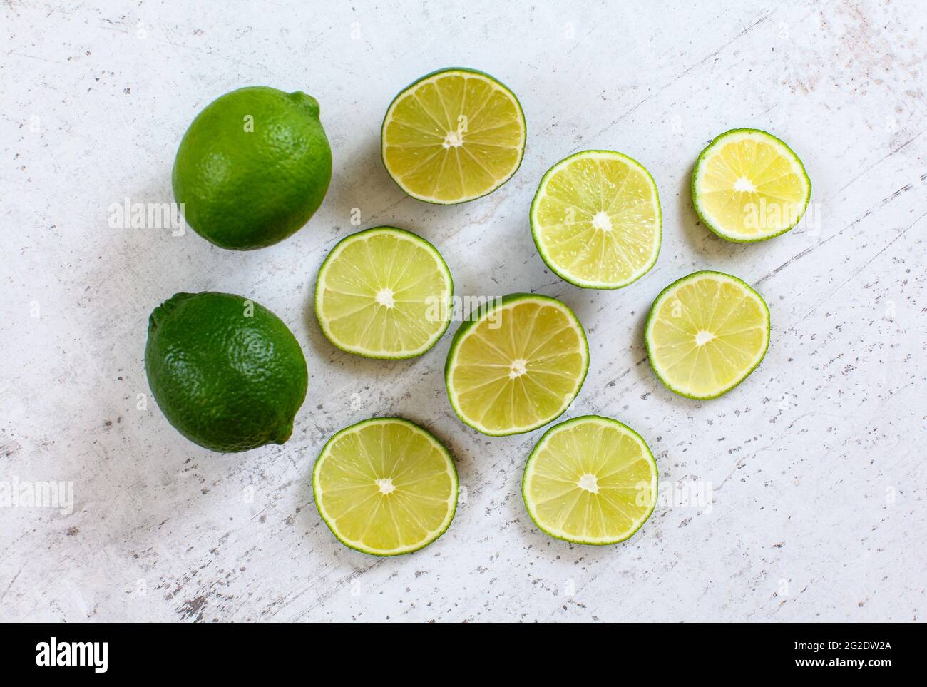 Lime intero e agrumi affettati su pietra bianca come scrivania, vista dall'alto Foto Stock