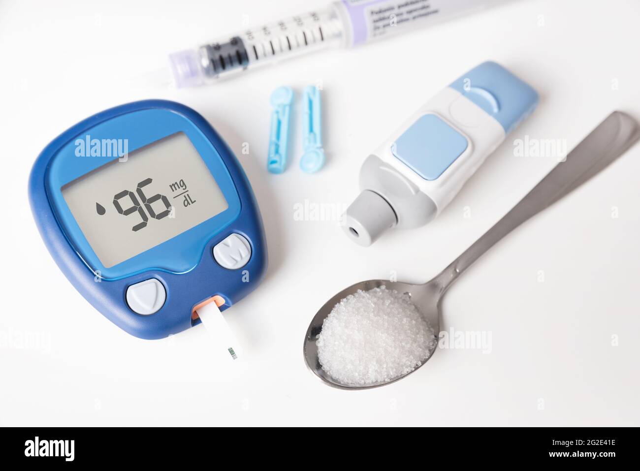 Trattamento e controllo del diabete concetto. Glucometro, cucchiaio con zucchero. Foto Stock