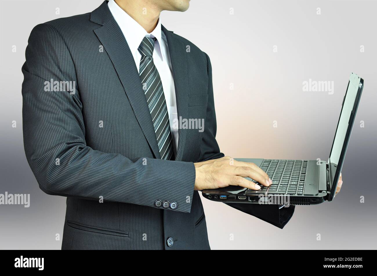 Uomo d'affari che tiene e dattilografa il laptop Foto Stock