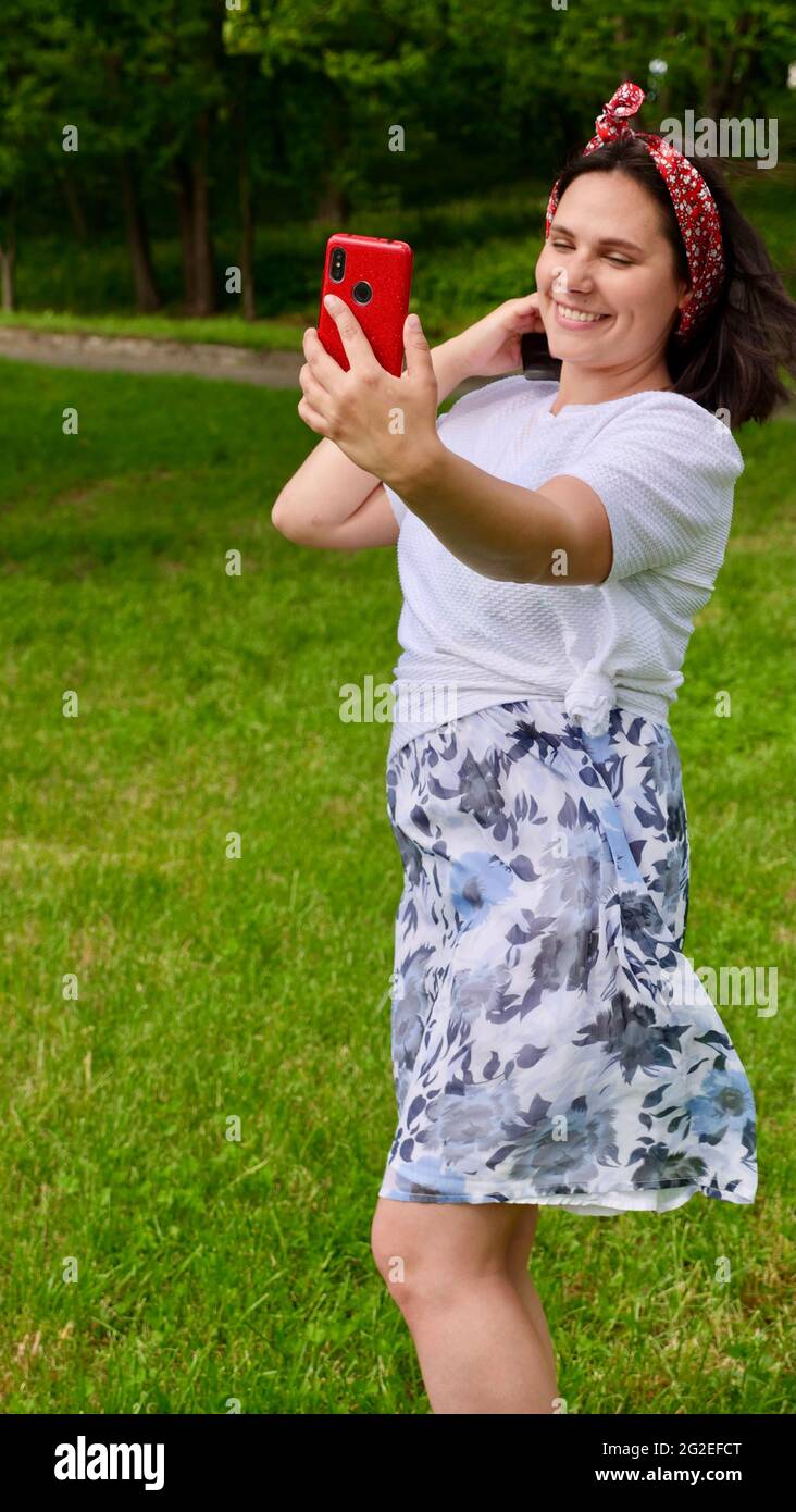 Bruna sorridente giovane donna che tiene un raschietto di giada di quarzo naturale, massaggiando la sua pelle per liberarsi di puffiness e cerchi scuri. La ragazza fa una routine di cura della pelle. Foto verticale Foto Stock