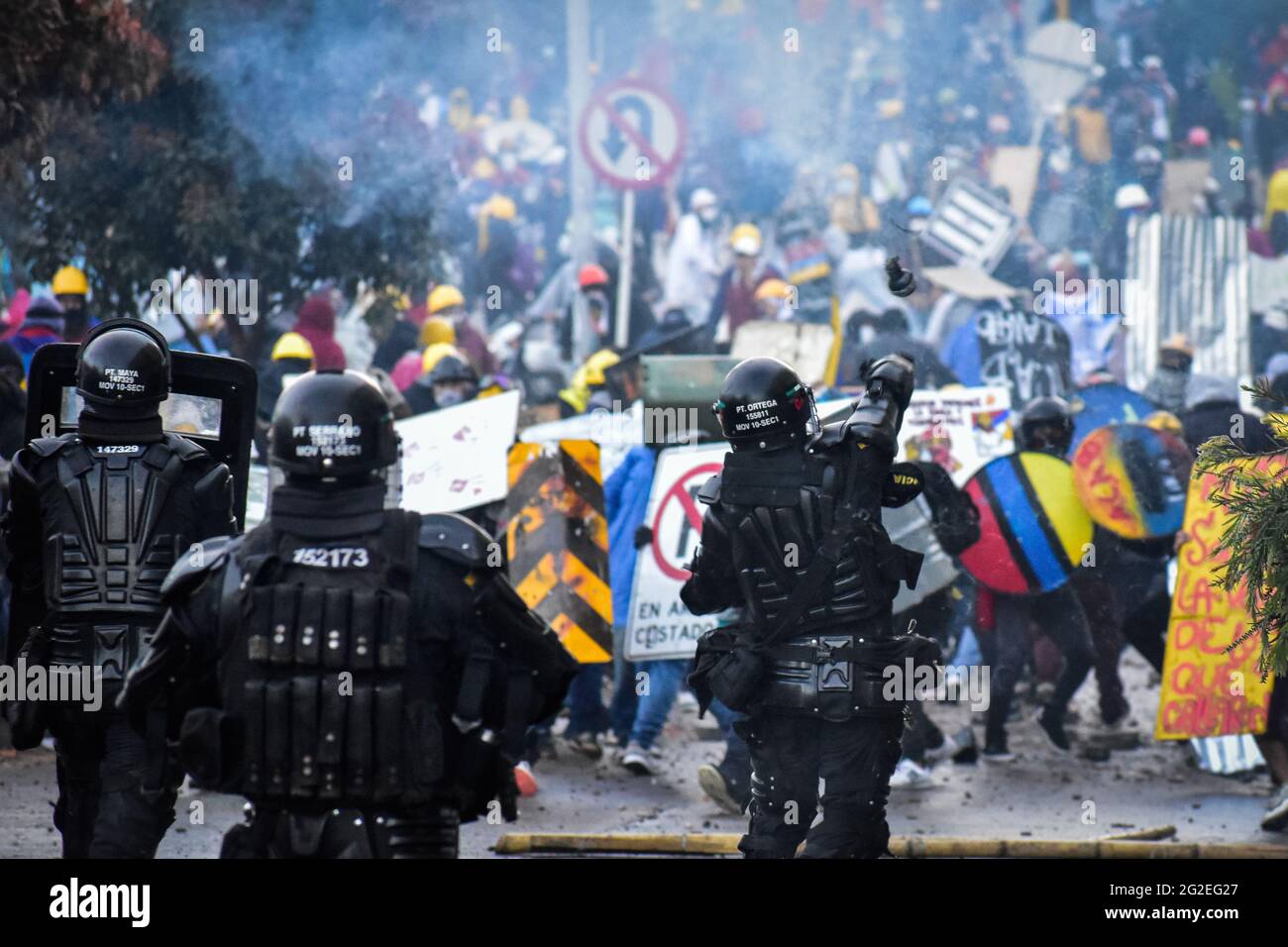 Un ufficiale della polizia in rivolta (ESMAD) della Colombia lancia un gas di trar e una granata di acrobazie ai dimostranti durante gli scontri, mentre le manifestazioni si intensificavano per disordini e scontri tra dimostranti e la polizia in rivolta della Colombia admisero dimostrazioni anti-governative contro il presidente della Colombia Ivan Duque, la brutalità e le disuguaglianze della polizia a Pato, Colombia, il 9 giugno 2021. Foto Stock