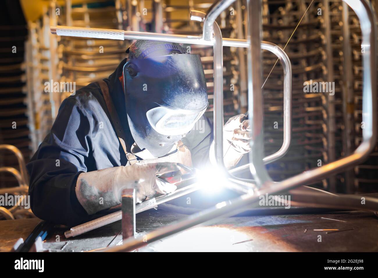 Saldatore che costrue acciaio in uno stabilimento di produzione. Artigiano del metallo che lavora nel suo ambiente di lavoro di ingegneria. Foto Stock