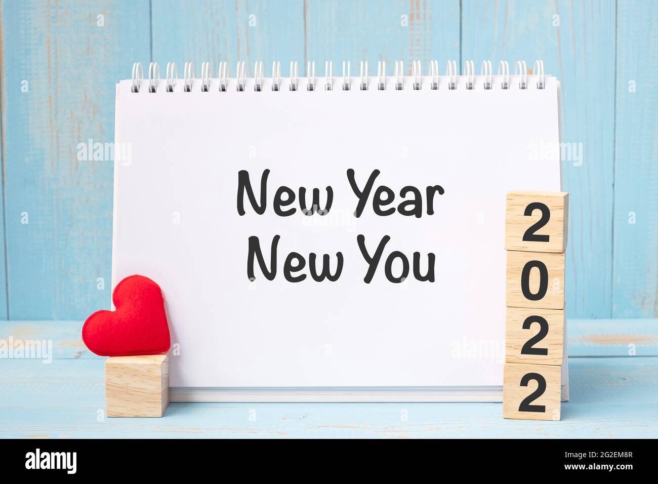 New Year New You parole e 2022 cubetti con decorazione a forma di cuore rosso su sfondo blu tavola di legno. Obiettivo, risoluzione, salute, Amore e buon Valente Foto Stock