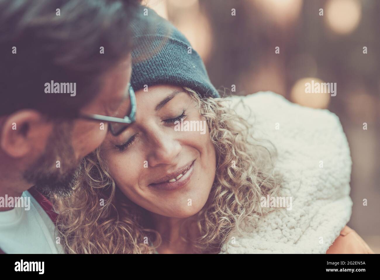 Romanticismo e tenerezza tempo per adulto giovane coppia insieme - ritratto di bella donna e uomo abbraccio e amore all'aperto con bokeh sfondo colorato Foto Stock
