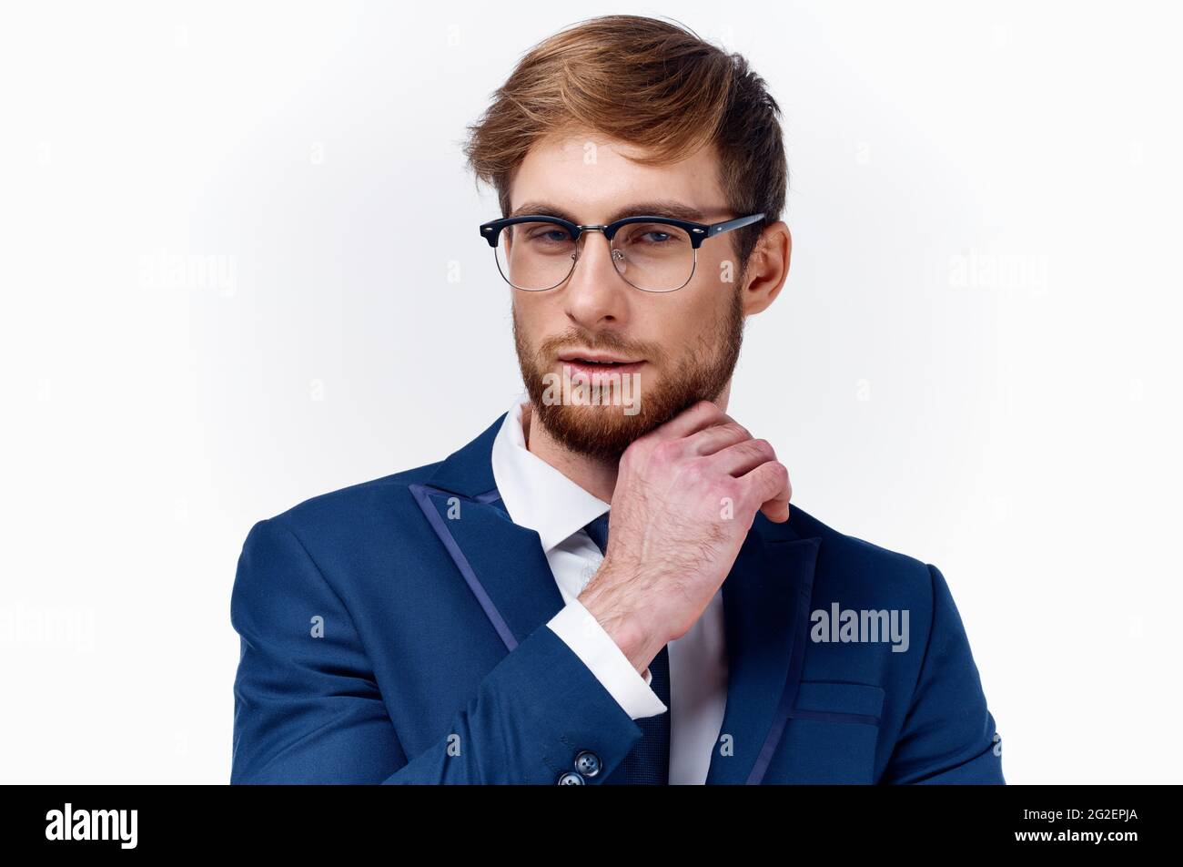 l'uomo d'affari in un vestito e gli occhiali la tiene la mano vicino al  viso su uno sfondo chiaro cravatta giacca blu classico Foto stock - Alamy