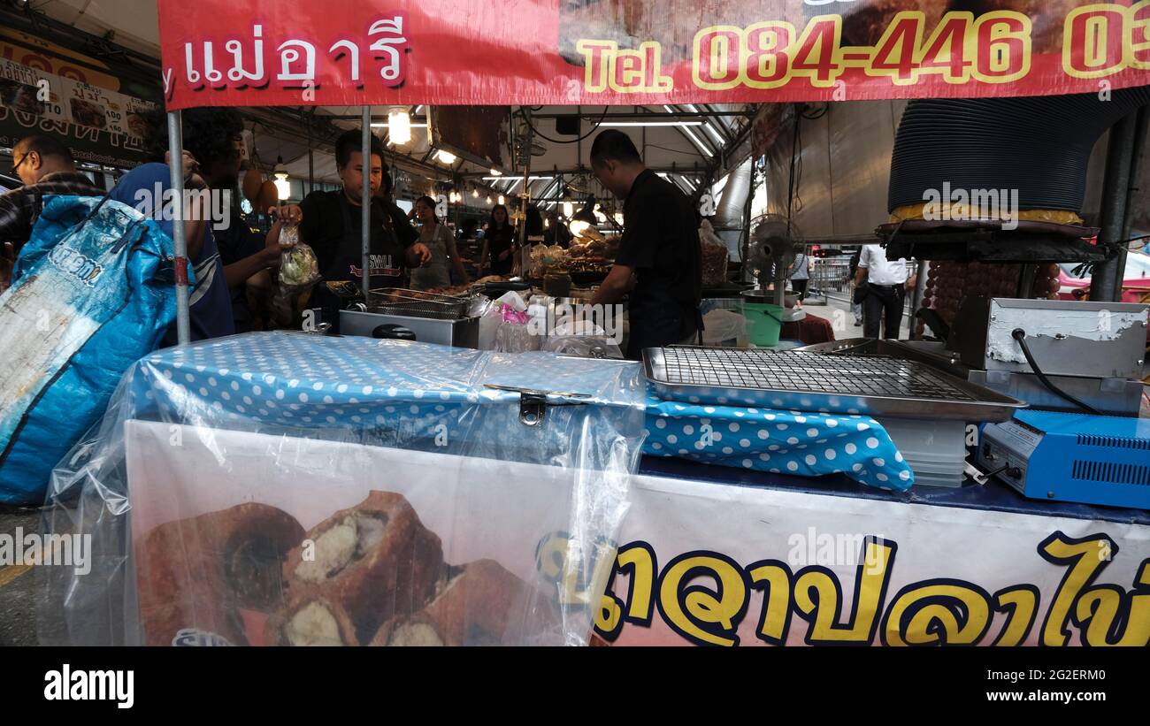 Basso costo pronto a mangiare Street Foodservice lavoratori in background. Sul davanti c'è un cart di cibo di stile che non viene usato HawkerBangkok Thailandia Foto Stock