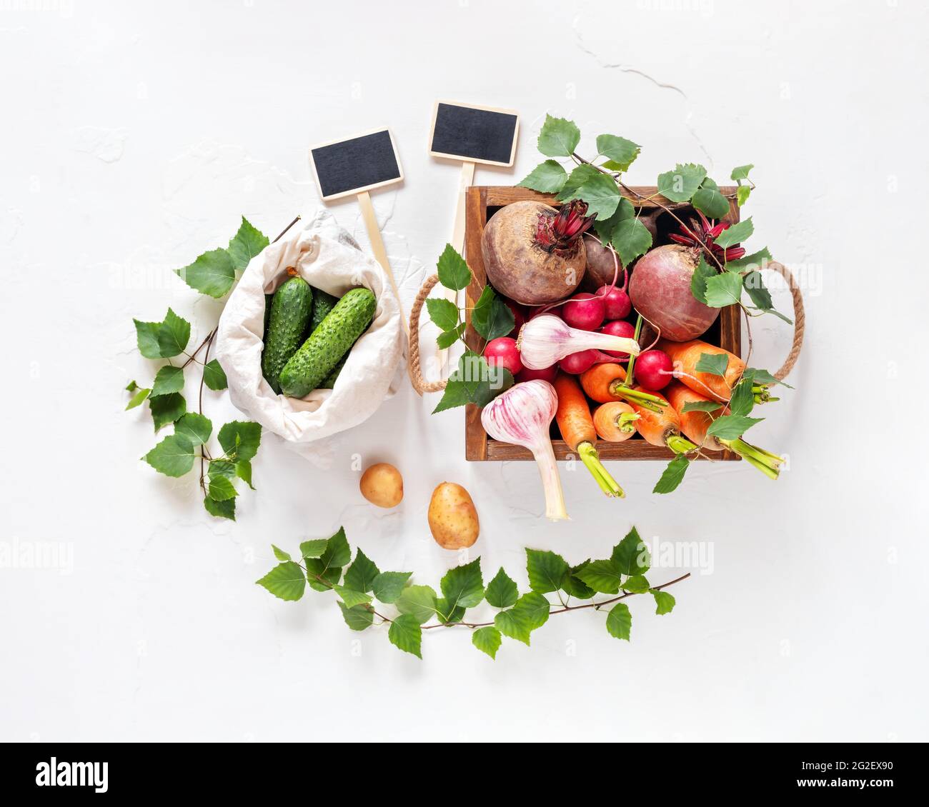 Vendita di verdure di stagione al mercato locale. Ortaggi naturali, da fattoria, in un imballaggio ecologico con scritture su sfondo bianco Foto Stock