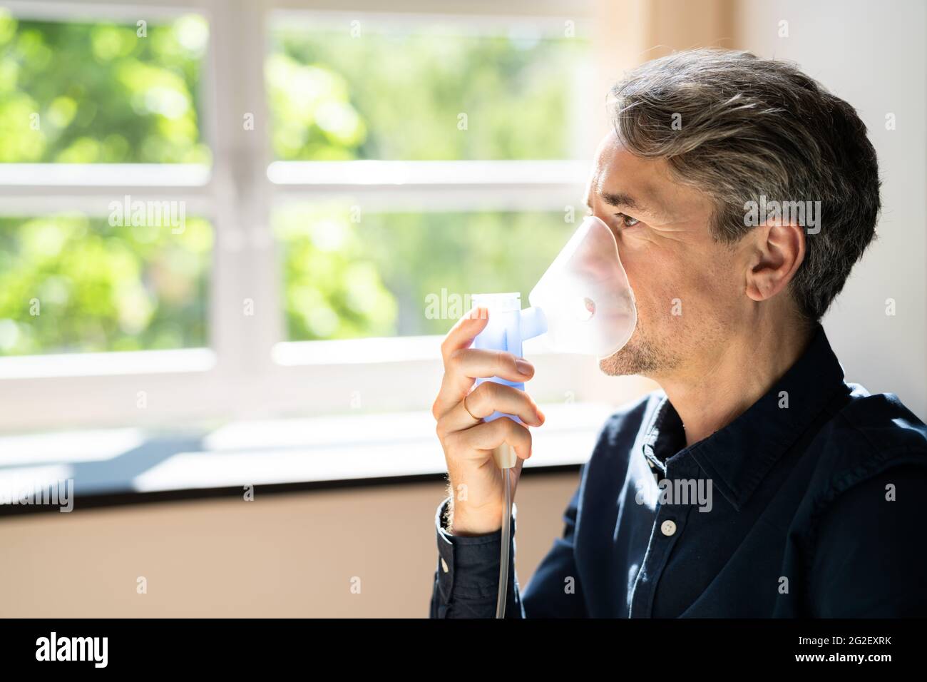 Maschera di ossigeno per malattie polmonari e fibrosi. Uomo che inala Foto Stock