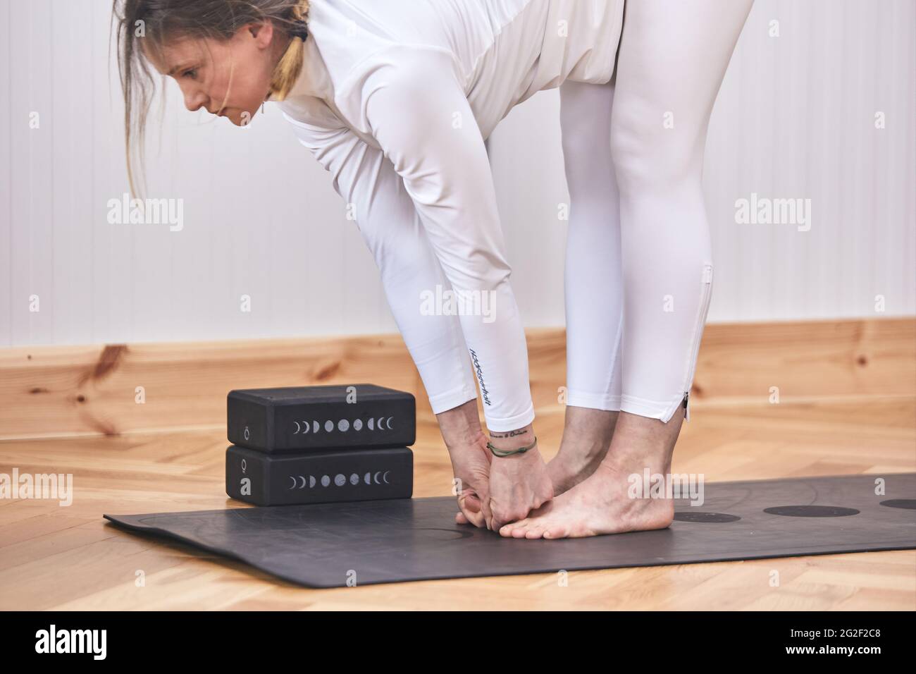 Donna latina facendo Forward Bend Yoga posa, Padangusthasana. In palestra Foto Stock
