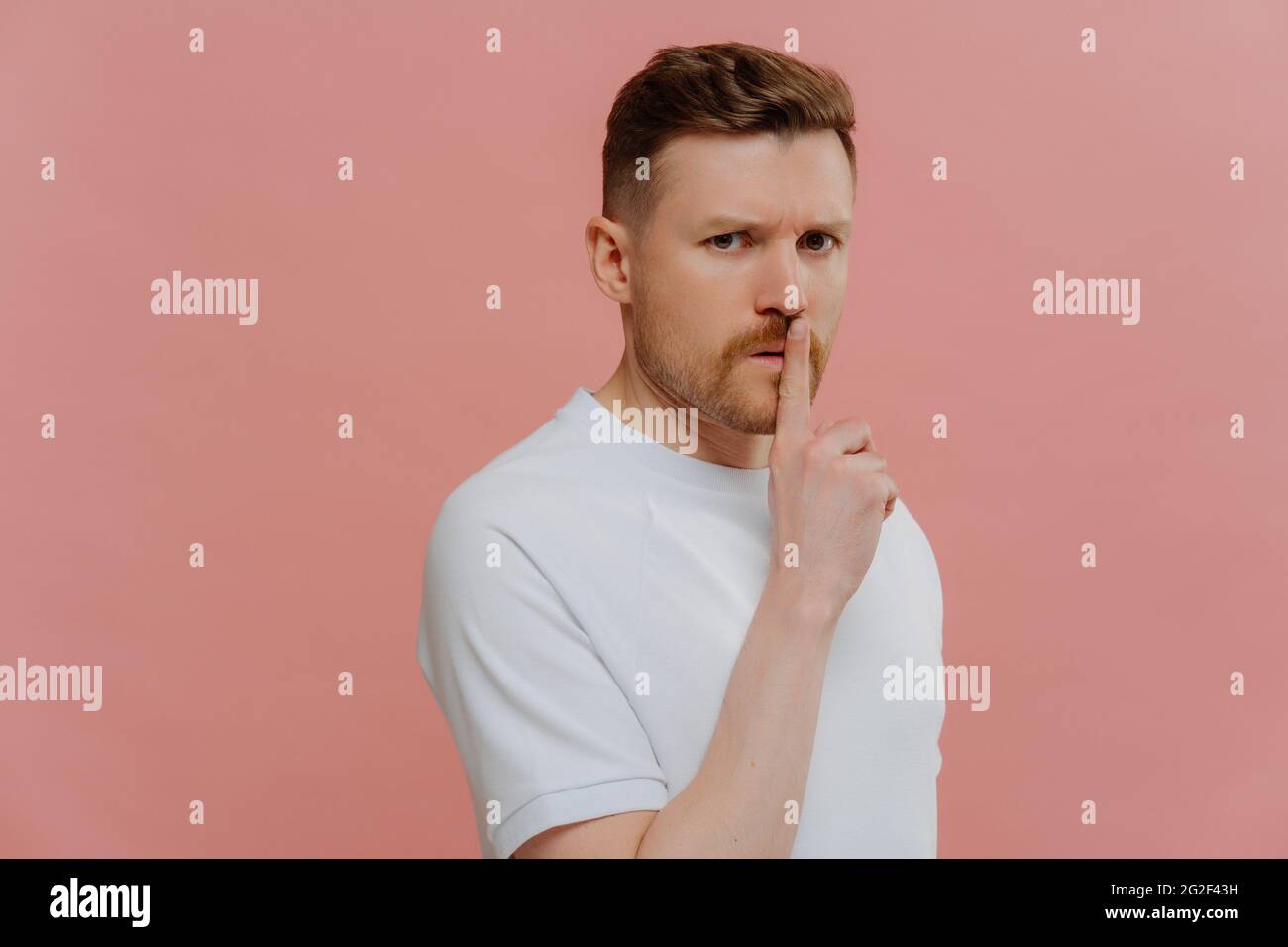Giovane uomo misterioso in camicia bianca che chiede di mantenere le informazioni in segreto Foto Stock