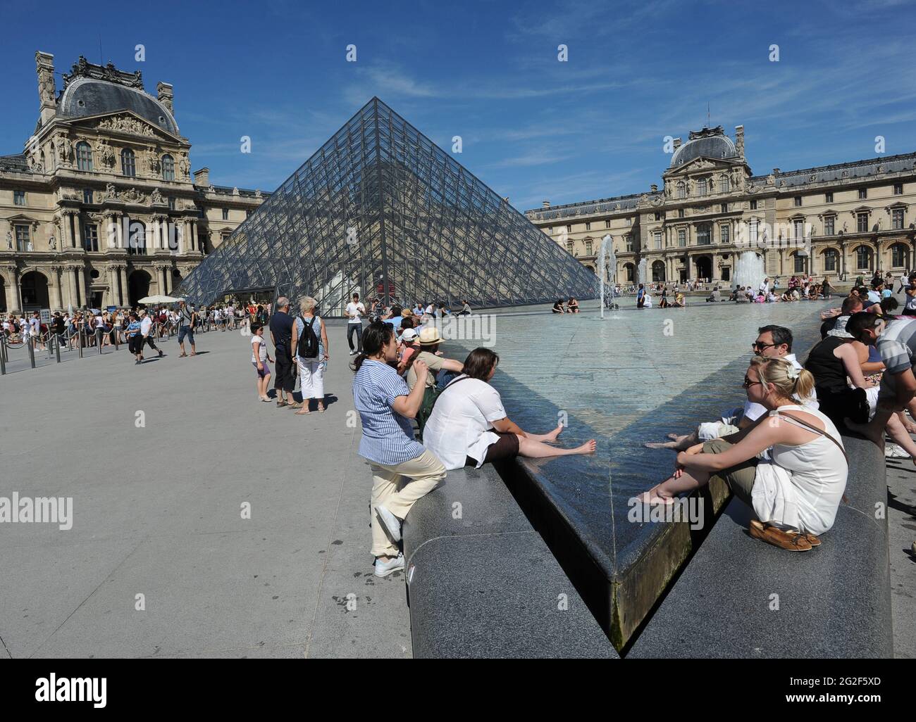 I turisti rinfrescano i piedi fuori dal Louvre a Parigi Francia. Mostra turisti visitatori persone in visita europa cultura turistica europea Foto Stock