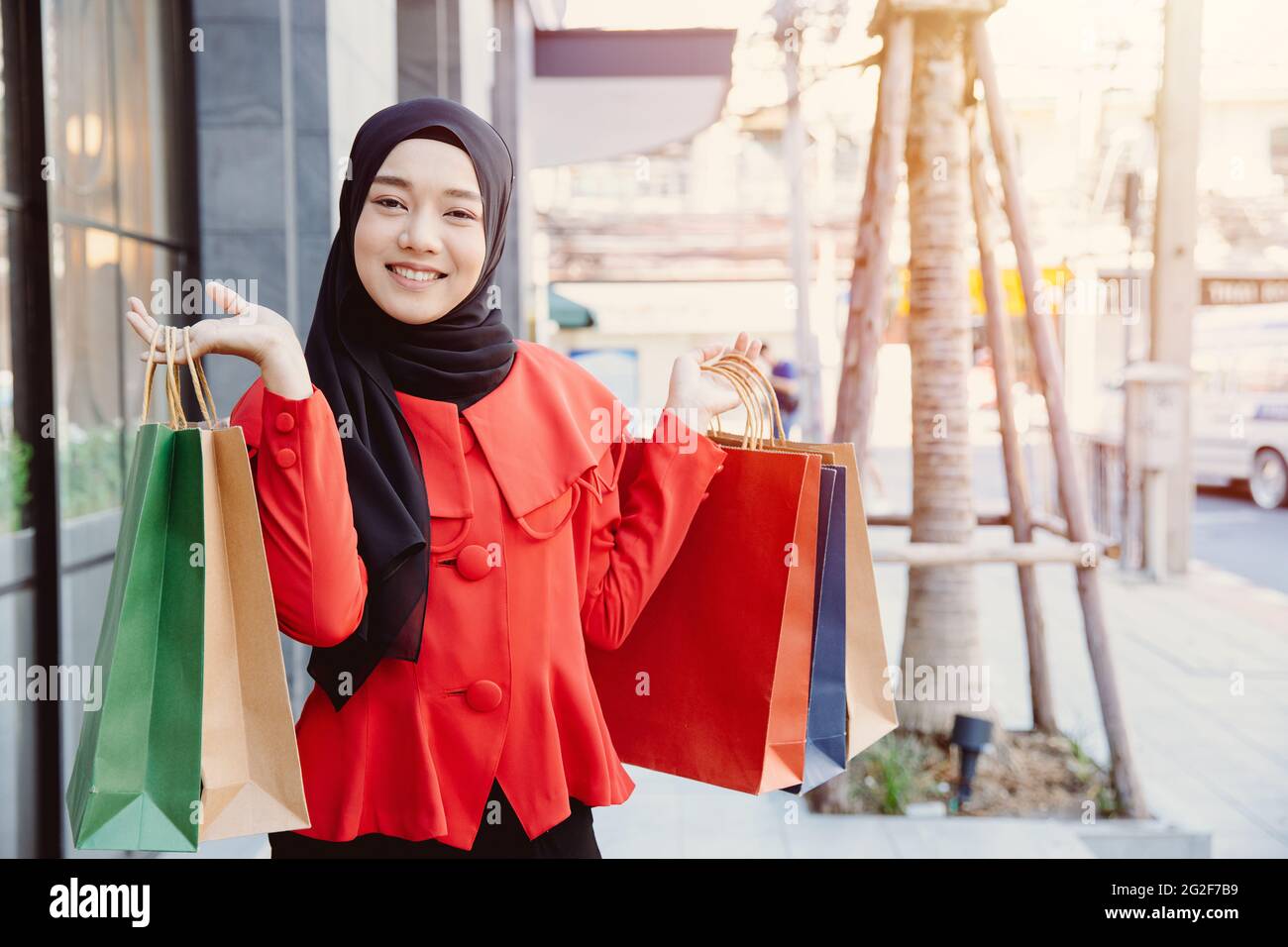 Giovane donna musulmana araba in abiti di velo hijab che tengono borse per lo shopping nella strada pedonale della metropolitana della città. Foto Stock