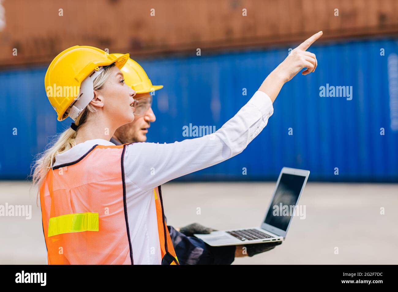 Il team dei lavoratori logistici che lavorano nel trasporto di container portuali per l'esportazione e il monitoraggio delle merci d'importazione con computer portatile. Foto Stock