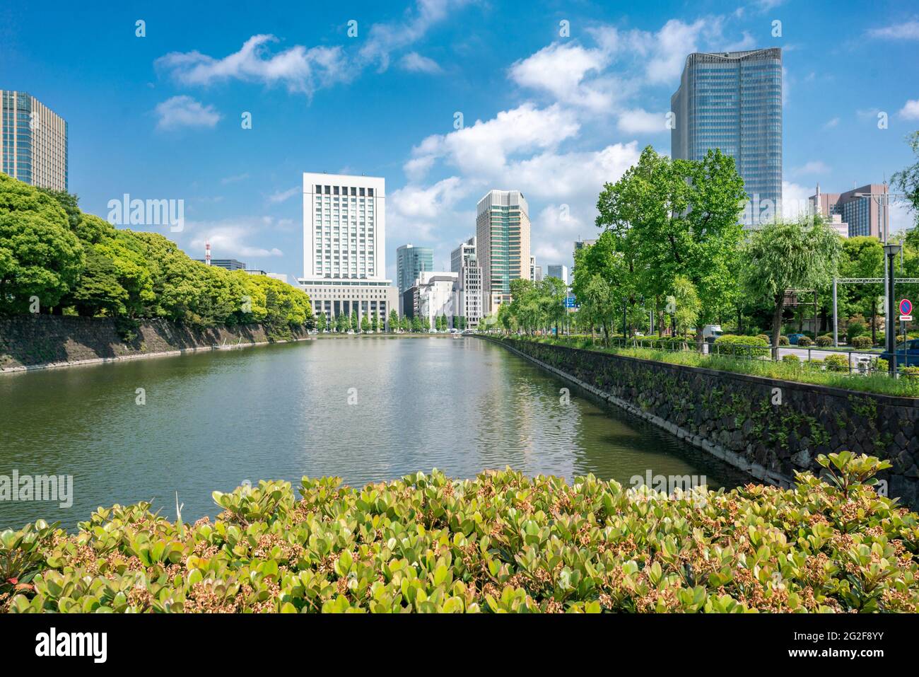 Tokyo, Giappone - 12.05.2019: Canale d'acqua e parete di pietra del complesso del Palazzo Imperatore visto dal Ponte di Iwaida. I grattacieli si riflettono nell'acqua Foto Stock