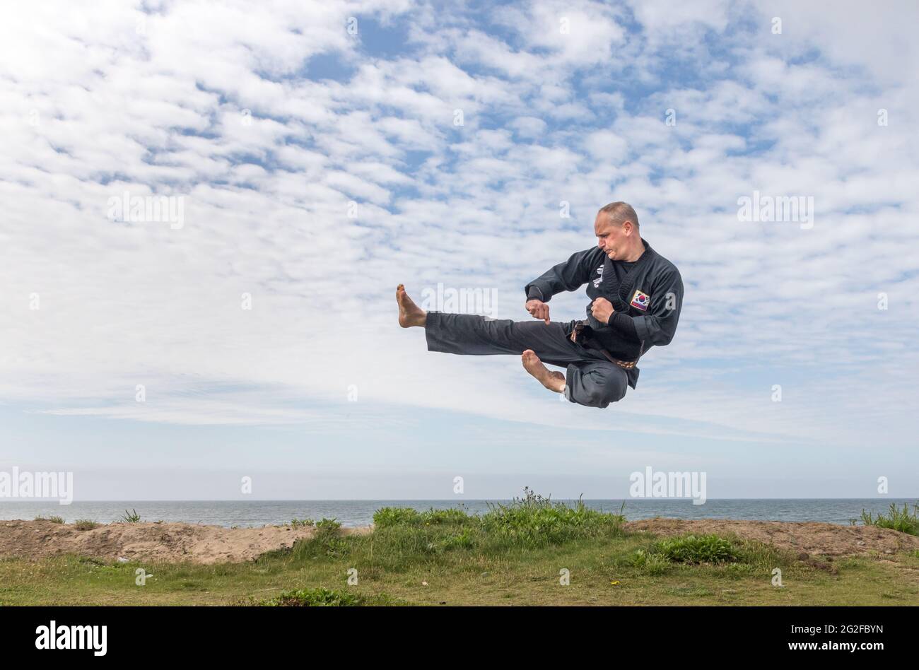 Garriluca, Cork, Irlanda. 11 Giugno 2021. Matthew Boniwell di Ballinspittle, un maestro di cintura nera di 5° grado nell'arte marziale coreana di Kuk Sool vinta, fa alcuni esercizi di riscaldamento prima di condurre una classe di mantenersi in forma sul lungomare di Garrylucas, Co. Cork, Irlanda. - credito; David Creedon / Alamy Live News Foto Stock