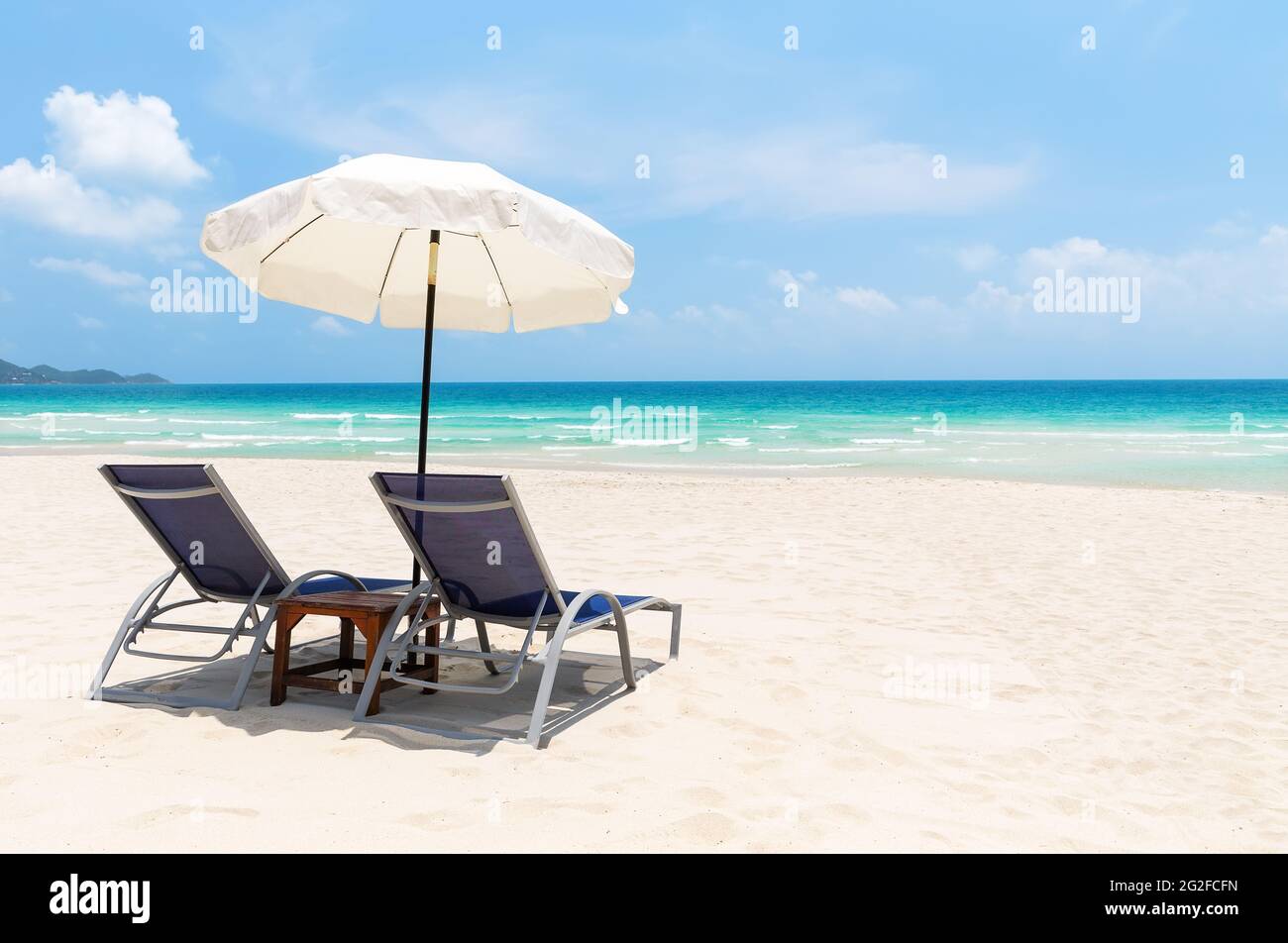 Sedie da spiaggia con ombrellone bianco e bella spiaggia di sabbia a Koh Samui, Thailandia. Vacanze di vacanza estate sfondo. Vista su una bella spiaggia tropicale. Foto Stock