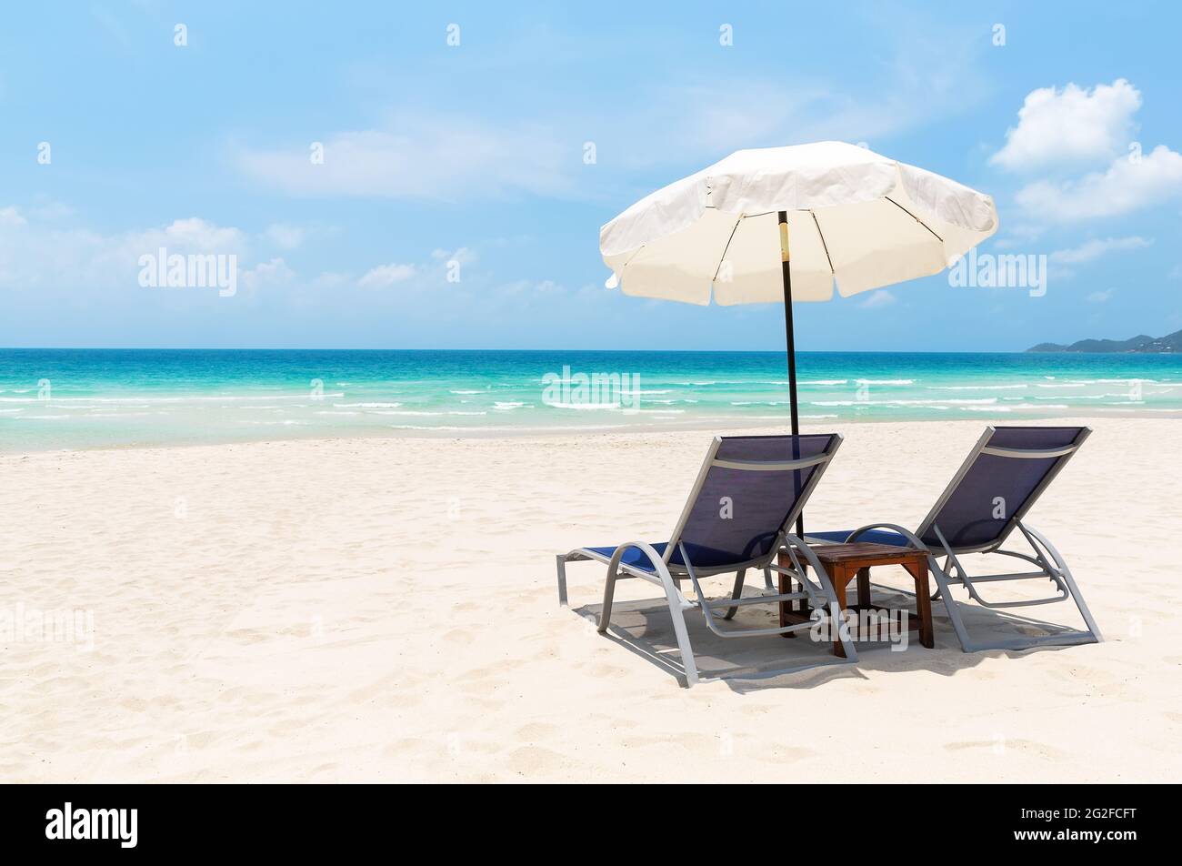 Sedie da spiaggia con ombrellone bianco e bella spiaggia di sabbia a Koh Samui, Thailandia. Vacanze di vacanza estate sfondo. Vista su una bella spiaggia tropicale. Foto Stock
