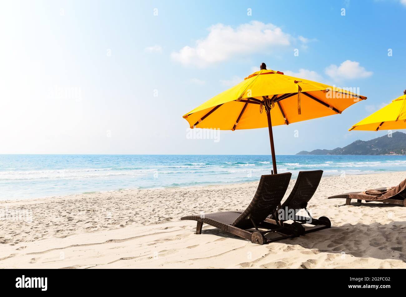 Sedie da spiaggia con ombrellone giallo e bella spiaggia di sabbia a Koh Samui, Thailandia. Vacanze di vacanza estate sfondo. Vista su una bella spiaggia tropicale. Foto Stock