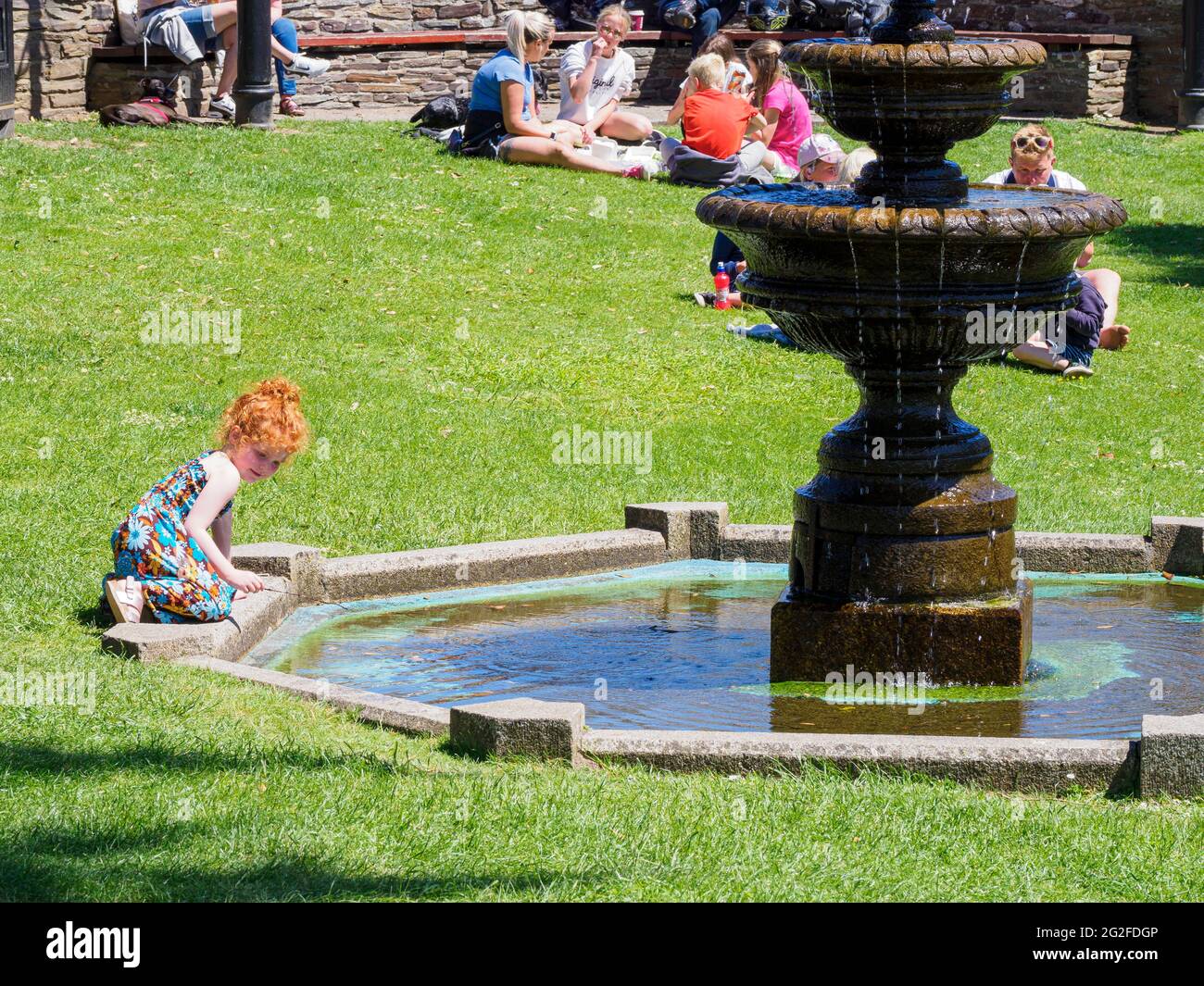 Giovane ragazza che gioca in una fontana pubblica al triangolo di Bude, Cornovaglia, Regno Unito Foto Stock