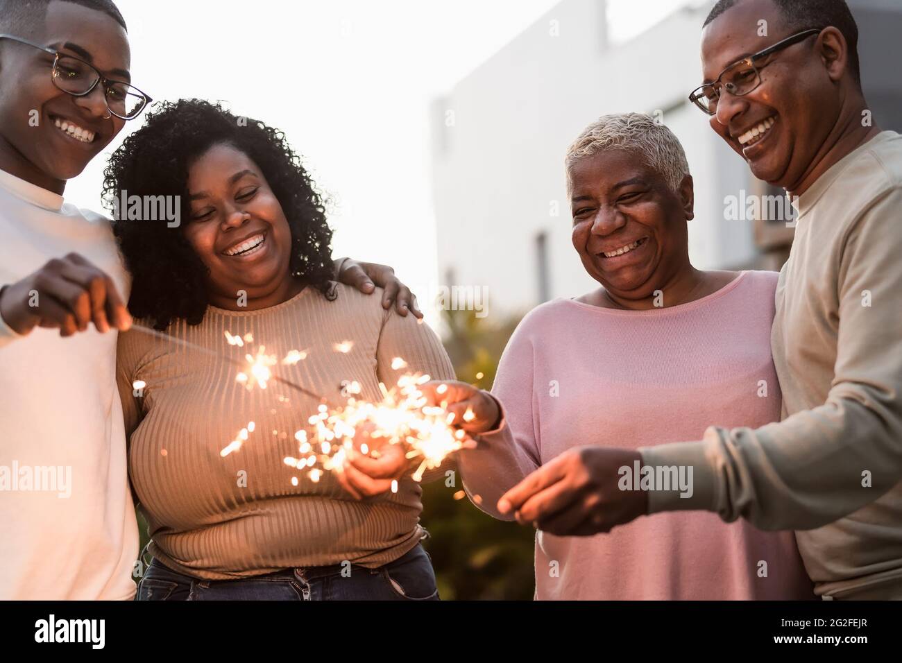 Felice famiglia africana festeggiando con sparklers fuochi d'artificio a casa festa - genitori unità e concetto di vacanza Foto Stock