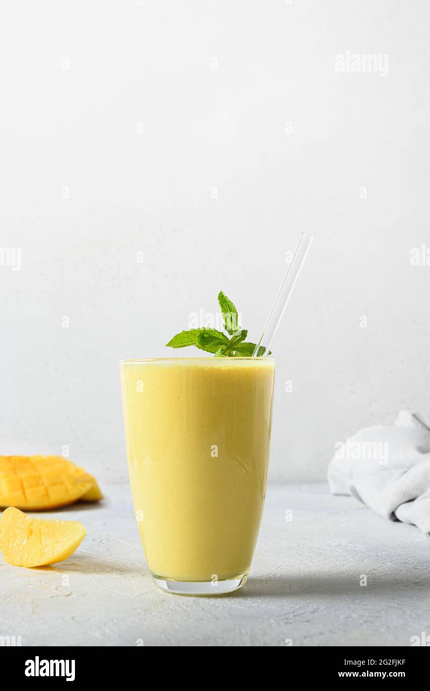 Mango indiano lassi su sfondo bianco. Verticale. Bevanda ayurvedica con mango. Freschezza lassi fatto di yogurt, acqua, spezie, frutta e ghiaccio. Foto Stock
