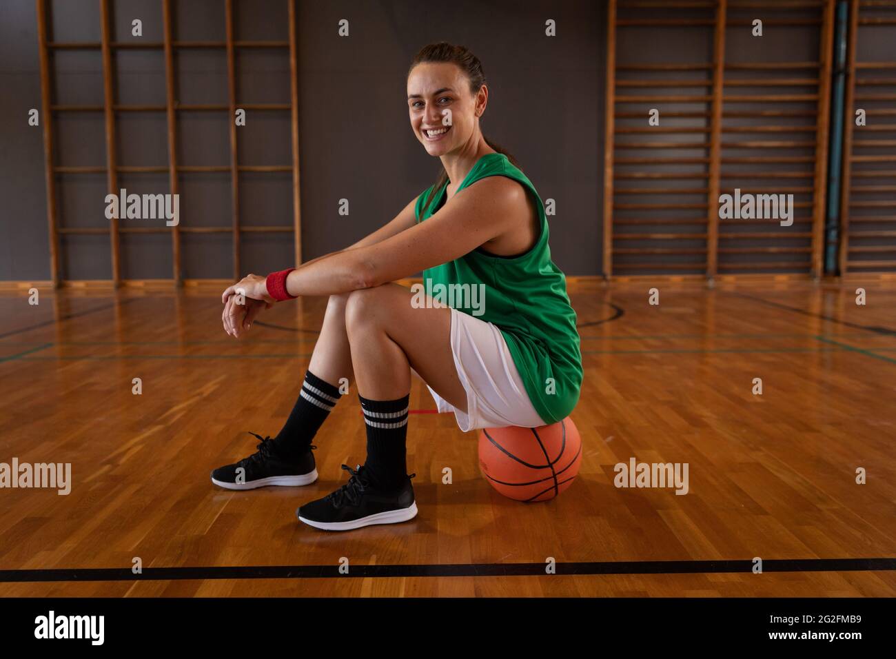 Ritratto di una donna caucasica di basket seduta sulla palla Foto Stock