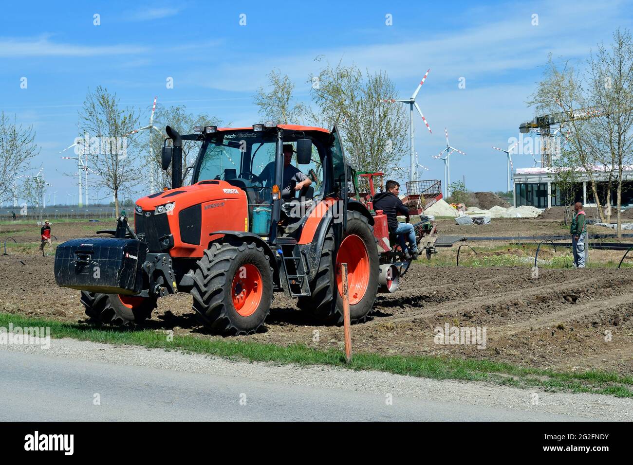 Podersdorf, Austria - 04 maggio 2021: Aiuti sconosciuti su un trattore che piantano vite meccanicamente Foto Stock