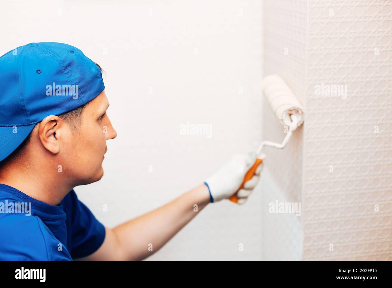 Un pittore dipinge un muro di cemento con vernice bianca, un maschio di  mano con un rullo di vernice per la verniciatura di una parete Foto stock -  Alamy