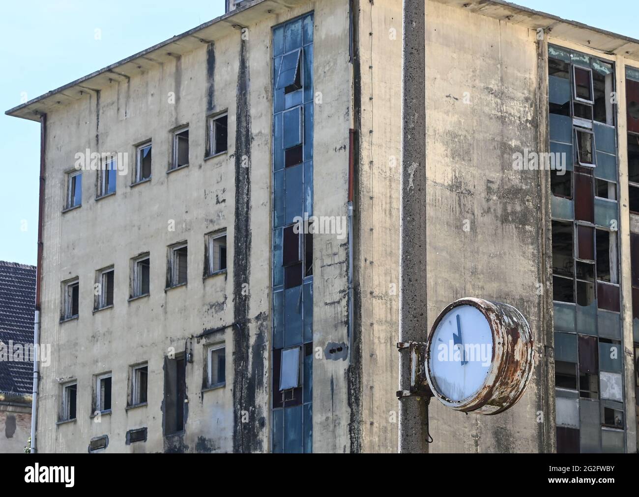 Pasewalk, Germania. 10 Giugno 2021. Un orologio intatto sulla base di un'ex impresa agricola della RDT di fronte a un edificio in via di dilatazione. Fino alla caduta del Muro, questo fu il sito di un impianto di miscelazione concentrato del VEB Getreidewirtschaft Pasewalk. L'orologio si fermò poco prima delle 11. Credit: Jens Kalaene/dpa-Zentralbild/ZB/dpa/Alamy Live News Foto Stock