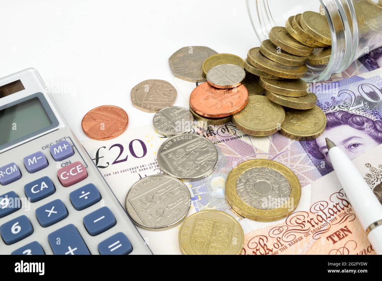 Una finanza ancora vita con un vaso di monete sterline su banconote sterline, calcolatrice e penna. Foto Stock