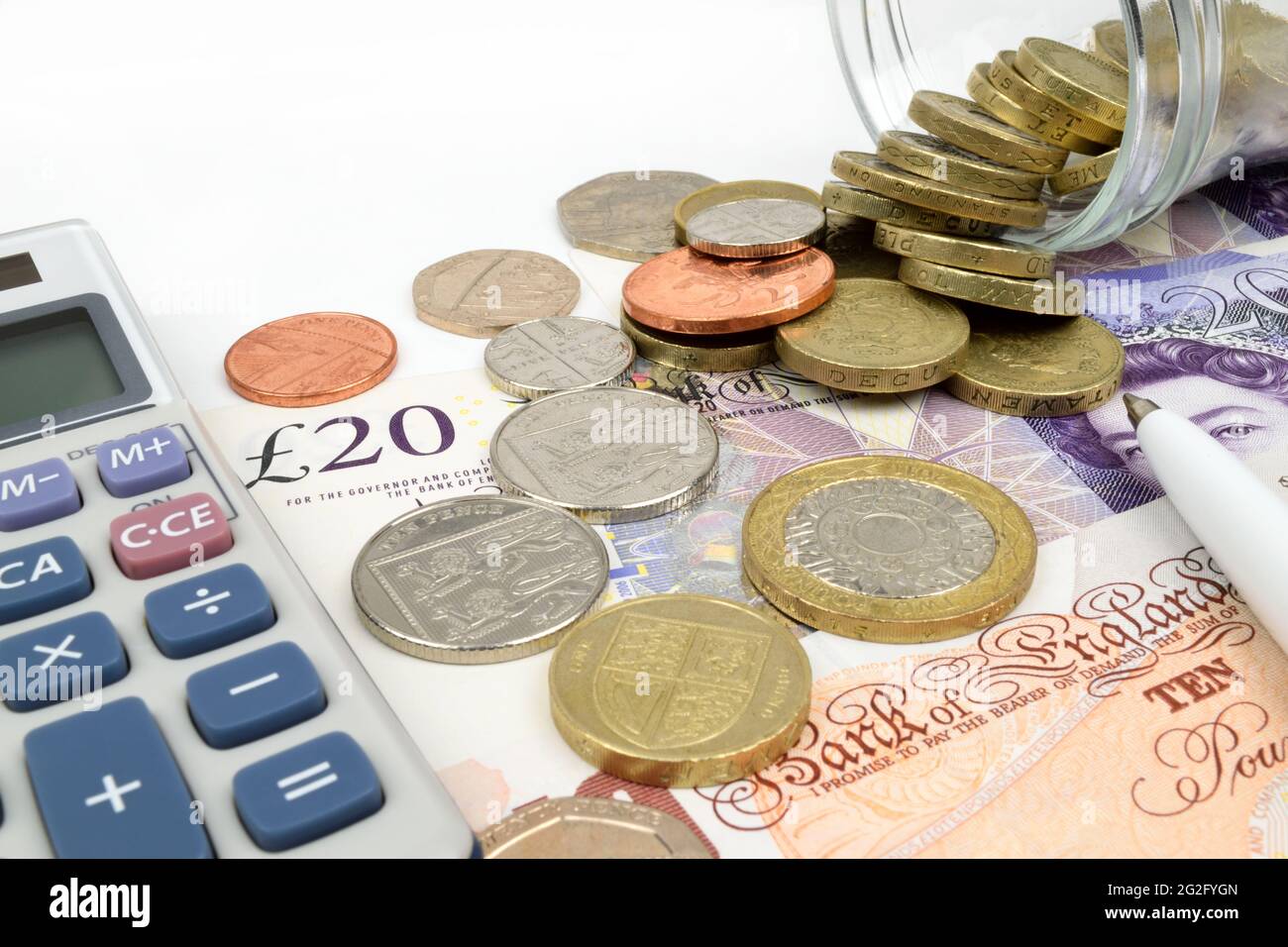 Una finanza ancora vita con un vaso di monete sterline su banconote sterline, calcolatrice e penna. Foto Stock